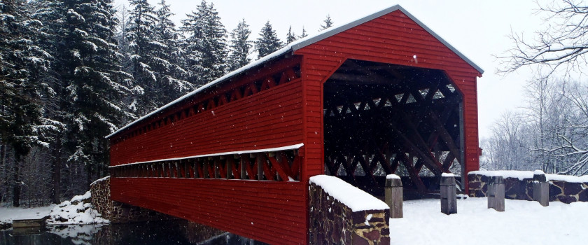 A red covered bridge in the snow.
