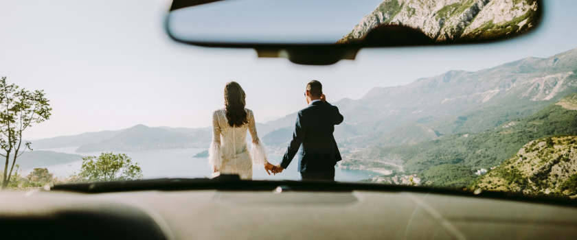 View through the windshield of a honeymooning couple overlooking a lake beneath mountains